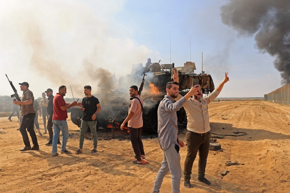 Palestinians take control of an Israeli tank after crossing the border fence with Israel from Khan Yunis in the southern Gaza Strip on October 7, 2023. — AFP pic