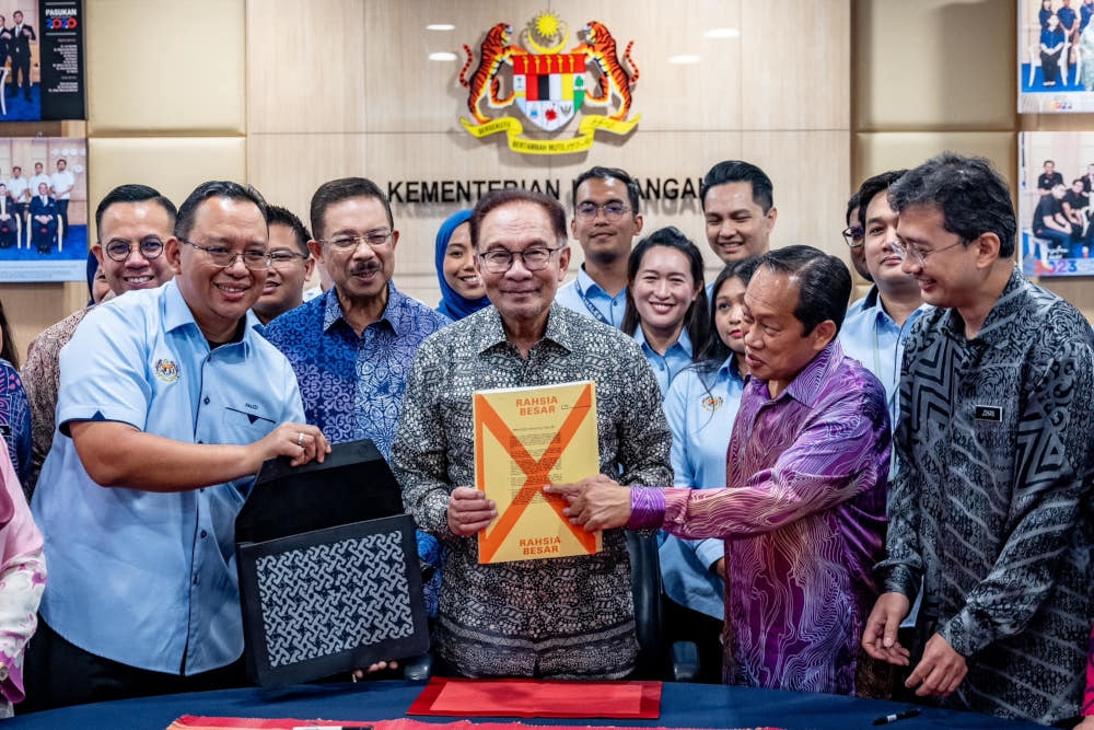 Prime Minister Datuk Seri Anwar Ibrahim poses for a group picture with MoF personnel involved in the Budget 2024 preparations before signing the top secret document which will be tabled at Parliament tomorrow. — Picture from Facebook/Anwar Ibrahim 