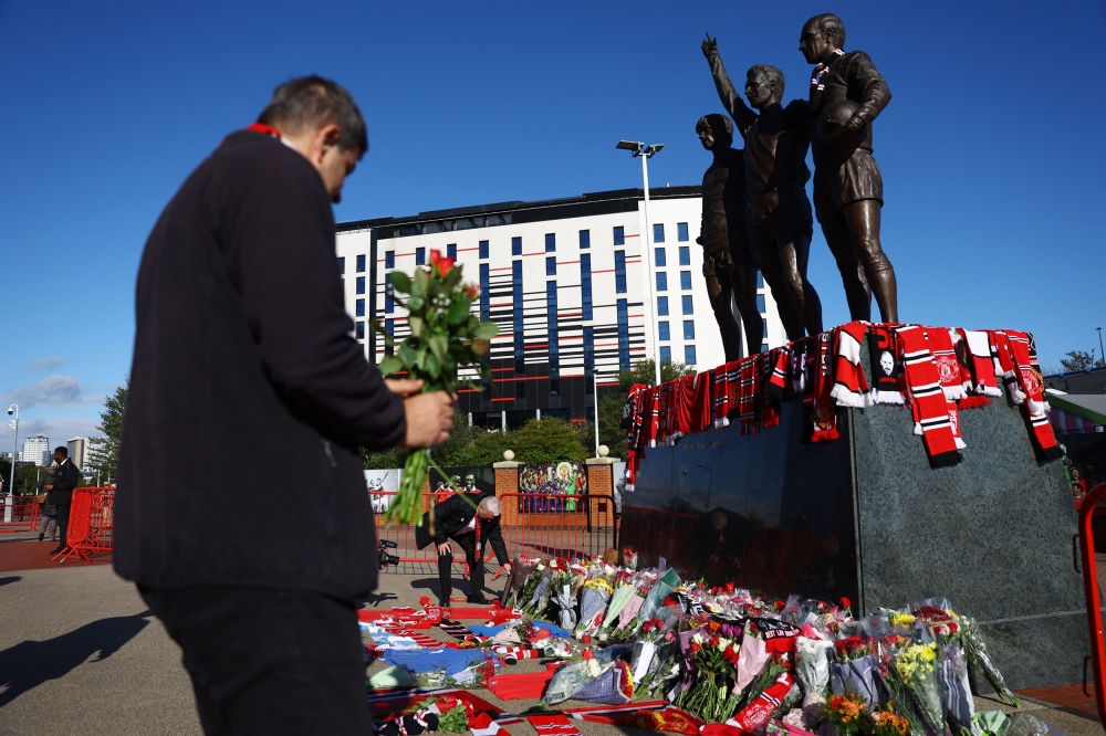 Fans gathered at Old Trafford today to remember Manchester United great Bobby Charlton laying flowers and scarves at the foot of the Trinity Statue. — Reuters pic