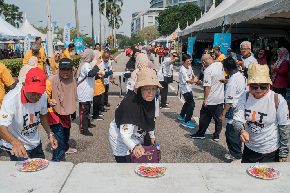 Senior citizens taking part in a rubber band relay on National Sports Day 2023 at Dataran Putrajaya. — Picture by Shafwan Zaidon