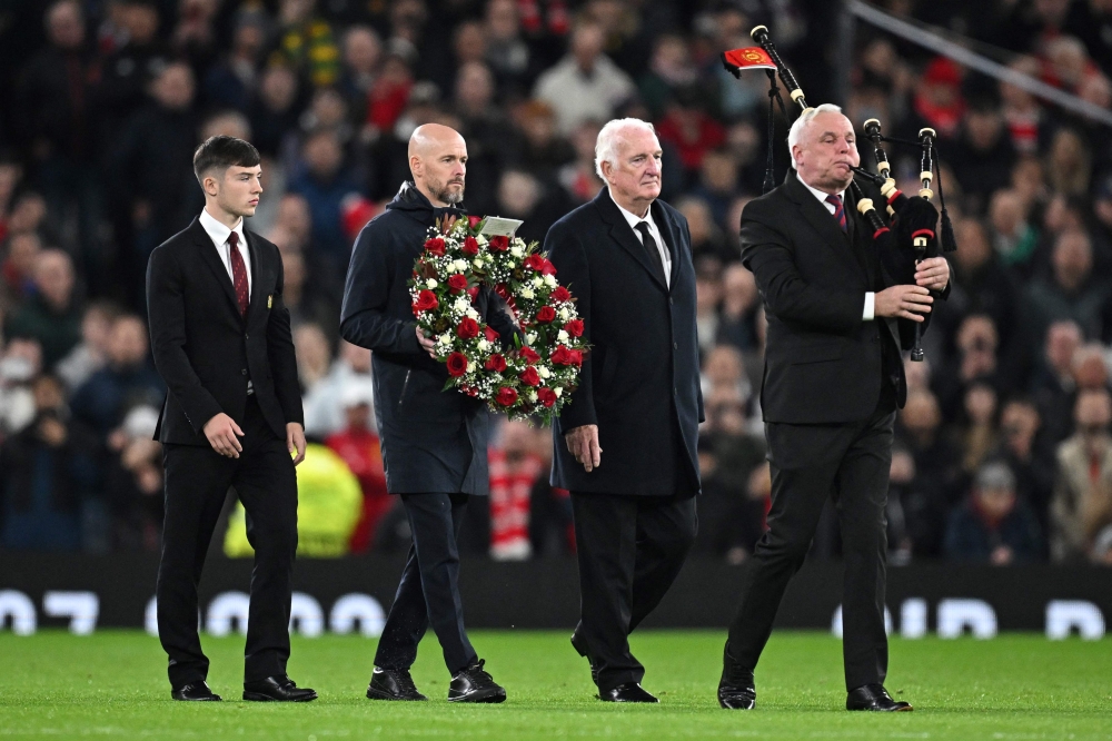 Manchester United's Dutch manager Erik ten Hag (second from left) carries a wreath of flowers next to former Manchester United's player Alex Stepney (second from right) and Manchester United youth player Dan Grove (left) as they are accompanied by a pipe player during a tribute to late Manchester United player Bobby Charlton who died at the age of 86, last weekend, ahead of the UEFA Champions League Group A football match between Manchester United and FC Copenhagen at Old Trafford, in Manchester  October 24, 2023. — AFP pic