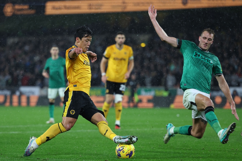 Wolverhampton Wanderers' South Korean striker #11 Hwang Hee-chan takes the ball past Newcastle United's English defender #33 Dan Burn (R) in the build-up to scoring their second goal during the English Premier League football match between Wolverhampton Wanderers and Newcastle United at the Molineux stadium in Wolverhampton, central England on October 28, 2023. — AFP pic