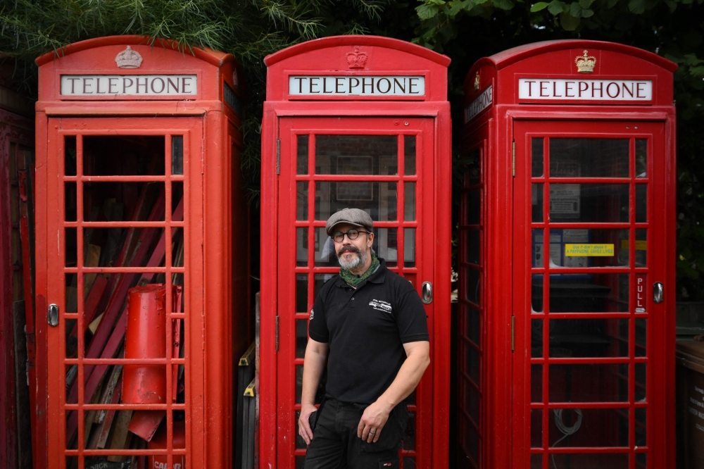 Owner Carl Burge, poses for a portrait in front of traditional red telephone boxes at 