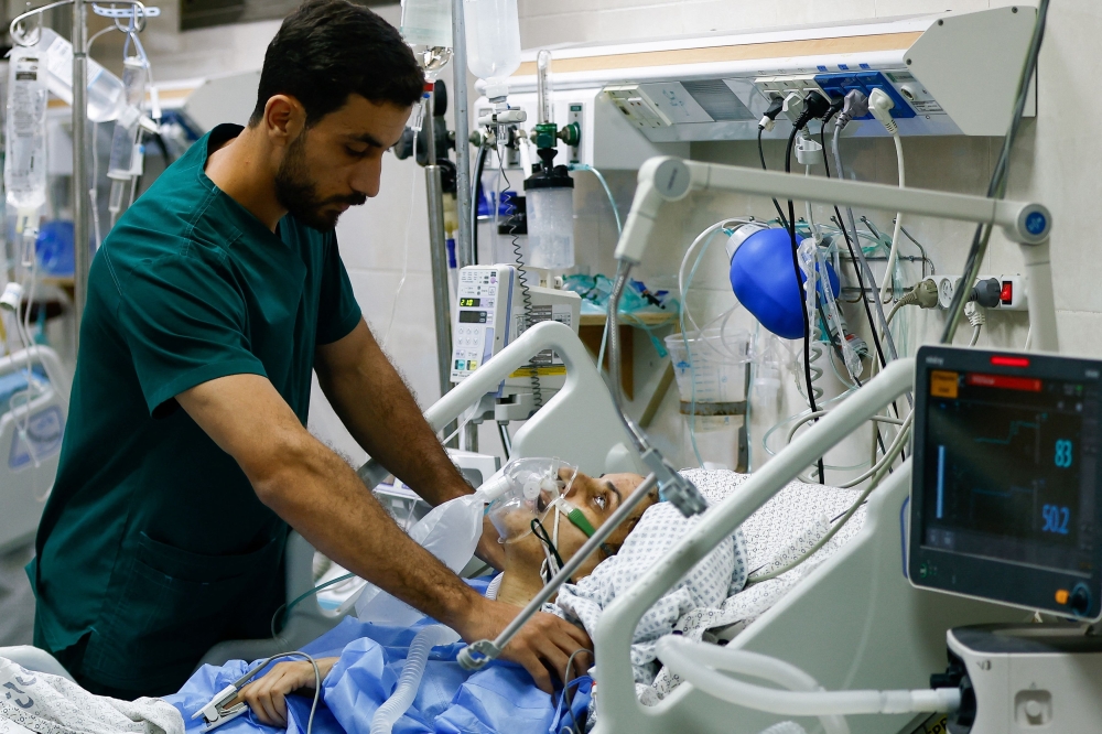 A medical worker assists a Palestinian, who was wounded in Israeli strikes, at the Intensive Care Unit (ICU) of Nasser hospital, as doctors say they are only able to accept critical cases that are in need of surgery, while the unit is filled up with victims of the ongoing conflict with Israel, in Khan Younis, in the southern Gaza Strip, October 26, 2023. — Reuters pic