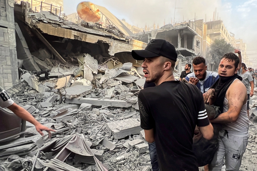 Palestinians carry a casualty at the site of Israeli strikes on houses, in Gaza City October 28, 2023. — Reuters pic