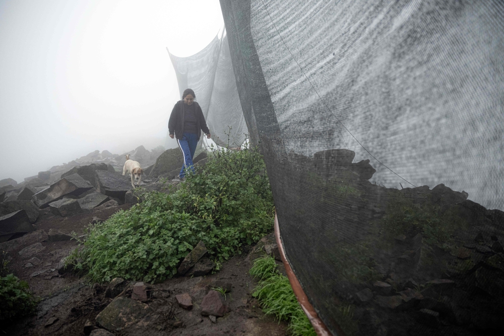 Sofia Llocclla Pellaca gets water from a fog catcher in Villa Maria del Triunfo district, on the southern outskirts of Lima, on October 7, 2023. — AFP pic