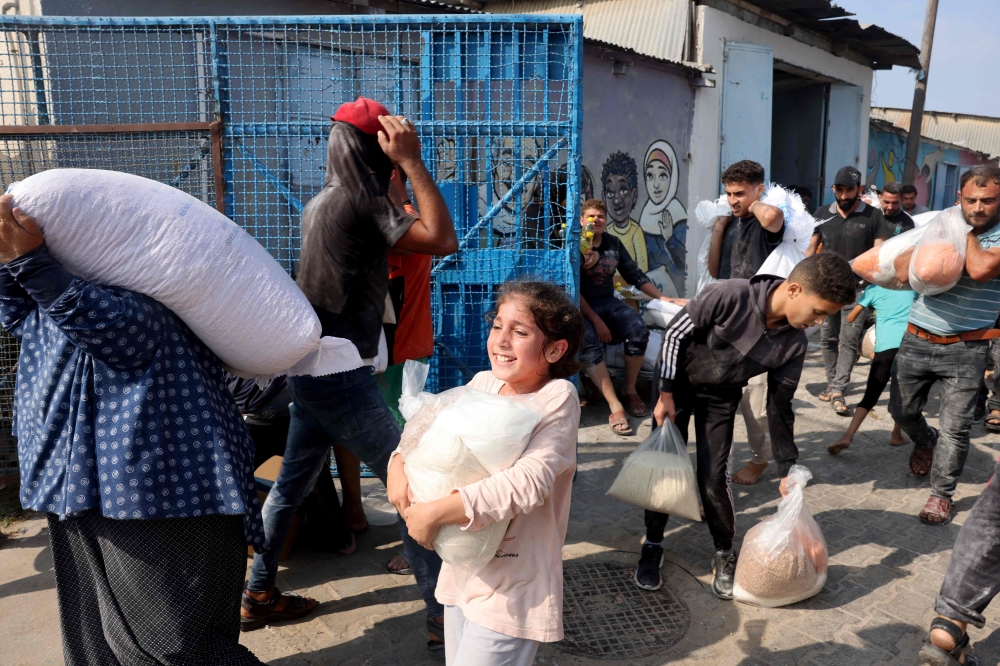 Palestinians at a UN-run aid supply centre that distributes food to displaced families following Israel’s call for more than one million residents in northern Gaza to move south. — AFP pic