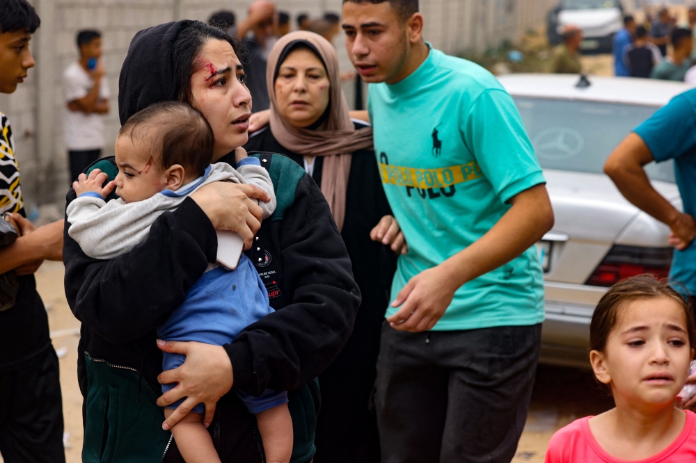 An injured woman carries a baby after Israel bombs Rafah in the southern Gaza Strip. — AFP pic