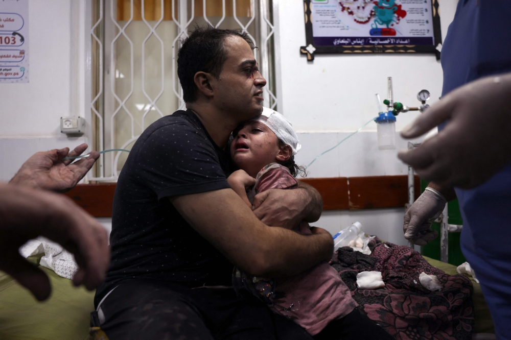 A Palestinian man cradles an injured child at the Najjar hospital following an Israeli air strike on a home in Rafah, in the southern Gaza Strip on October 30, 2023. — AFP pic 