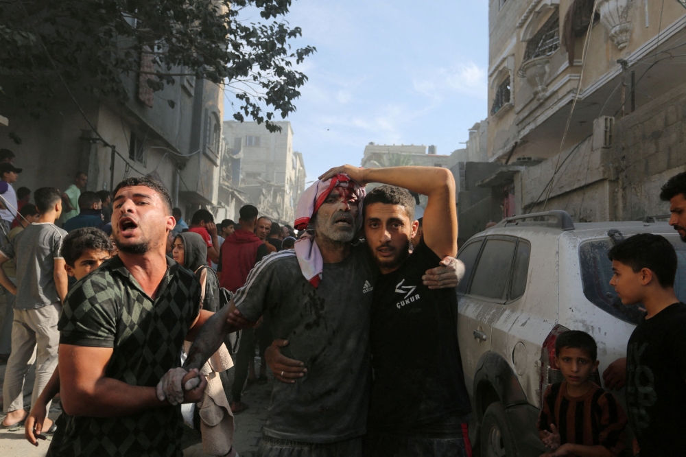 An injured Palestinian is assisted at the site of an Israeli strike on a house in Rafah in the southern Gaza Strip October 30, 2023. — Reuters pic