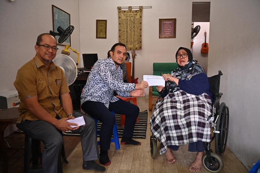 Prime Minister Datuk Seri Anwar Ibrahim’s political secretary Ahmad Farhan Fauzi (centre) hands over assistance to actress Fauziah Samad (right). — Picture via Facebook/Anwar Ibrahim