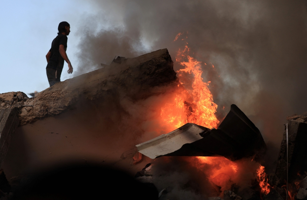 A Palestinian man stands on a concrete slab of a collapse building as a fire burns following the Israeli bombardment of Khan Yunis in the southern Gaza Strip on November 4 , 2023, amid the ongoing battles between Israel and the Palestinian group Hamas. — AFP pic