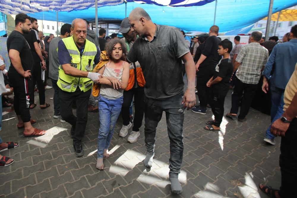 An injured girl is escorted by a man in his socks covered in dust and dirt, into Al-Shifa hospital following the Israeli bombardment of Gaza City’s Mansura neighbourhood, in the eastern suburb of Shujaiya on November 4, 2023, amid the ongoing battles between Israel and the Palestinian group Hamas. — AFP pic