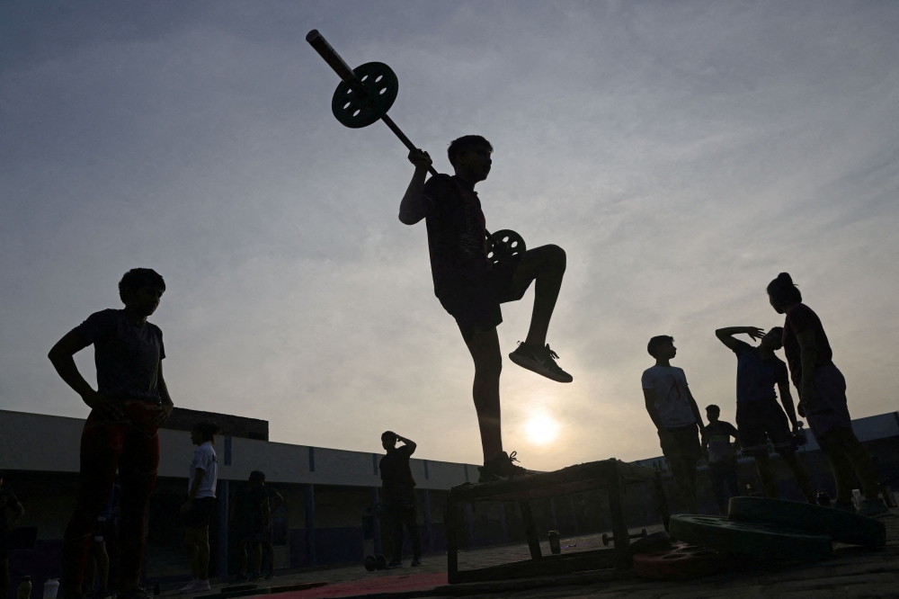 Aayush, 15, one of the three male students in Altius wrestling school, lifts weights and exercises during the morning fitness and practice session. — Reuters pic