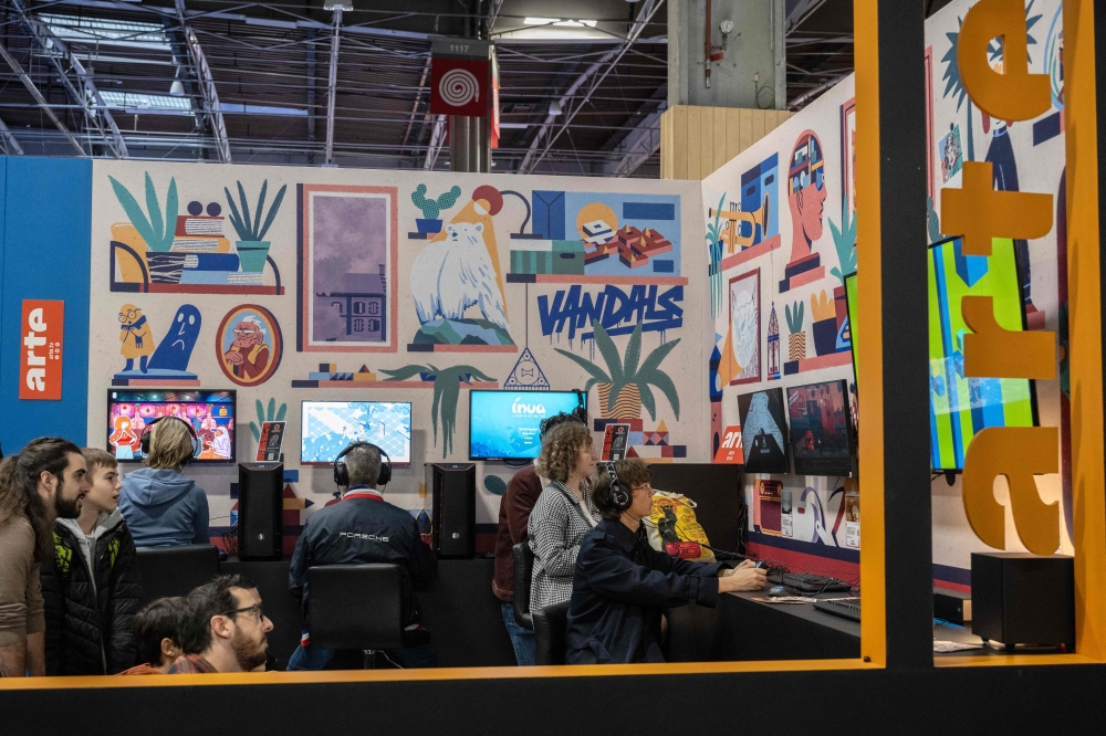 Visitors play video-games on the stand of the Franco-German public service channel Arte during the 