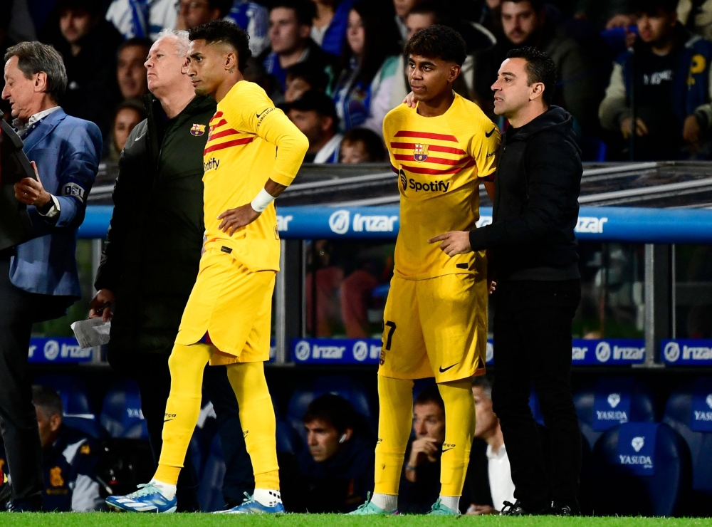 Barcelona's Spanish coach Xavi stands next to Barcelona's Spanish forward Lamine Yamal and Barcelona's Brazilian forward Raphinha on the sidelines during the Spanish league football match between Real Sociedad and FC Barcelona at the Anoeta stadium in San Sebastian November 4, 2023. — AFP pic