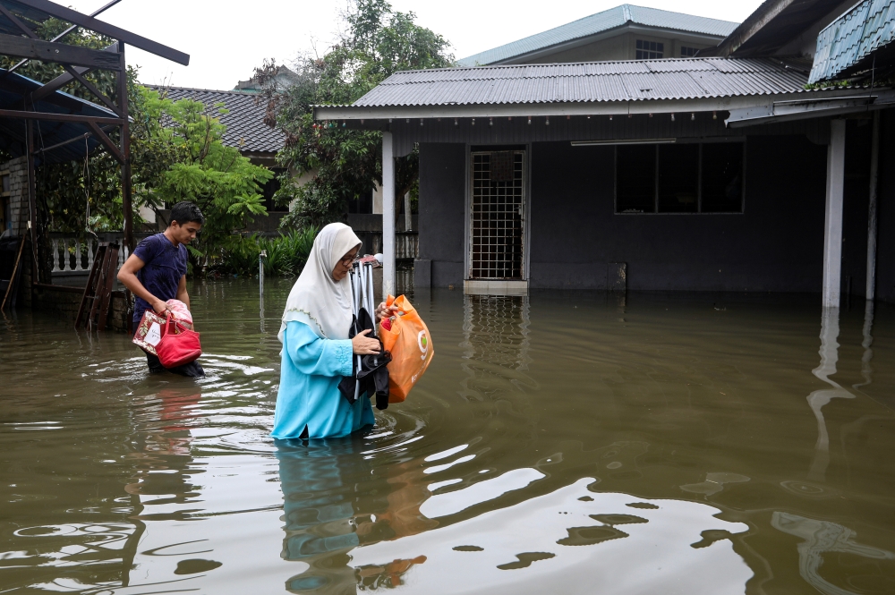 Wan Aizah Wan Ali, 52 and her son Sharul izmie Omar, 26 wade through floodwater at Kampung Titian Baru in Kuala Terengganu, November 22, 2023. — Bernama pic  