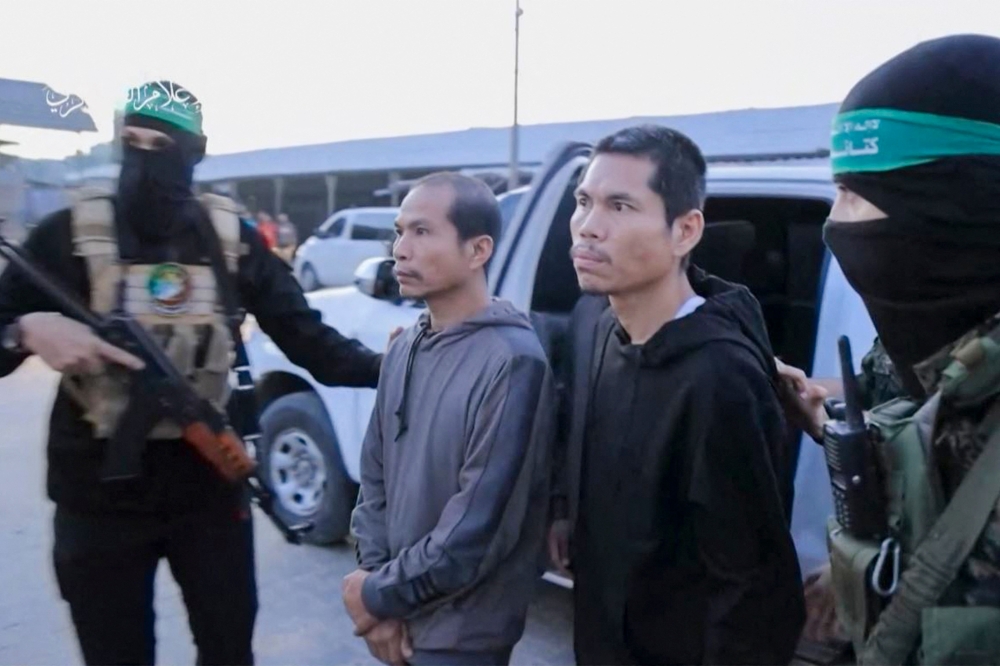 An image grab from a handout video released by the Hamas Media Office shows members of its Al-Qassam Brigades leading hostages over to officials from the International Committee of the Red Cross in Gaza on November 24, 2023, ahead of their transfer to Israel. — AFP pic