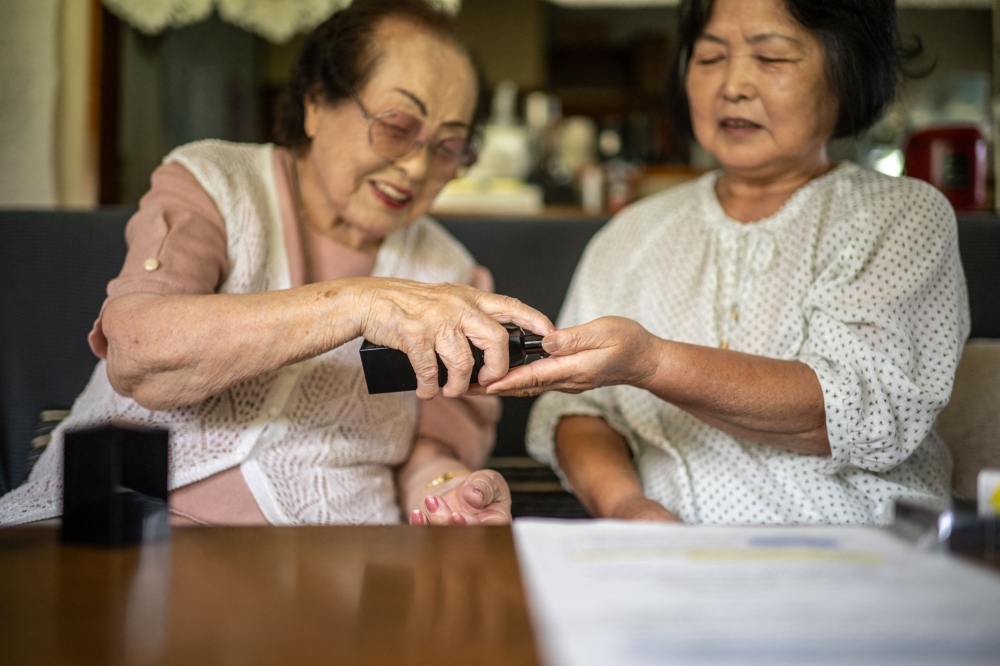 Tomoko Horino presenting products to her client Yuriko Abe at Abe's house in Fukushima city. — AFP pic