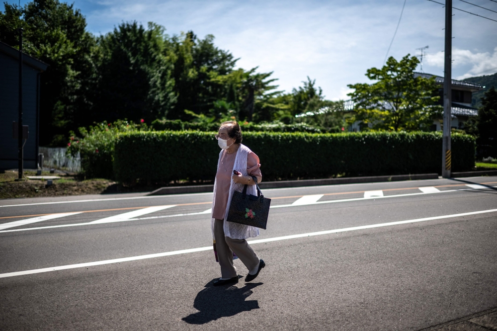  Tomoko Horino waiting for a bus to the office in Fukushima city. — AFP pic