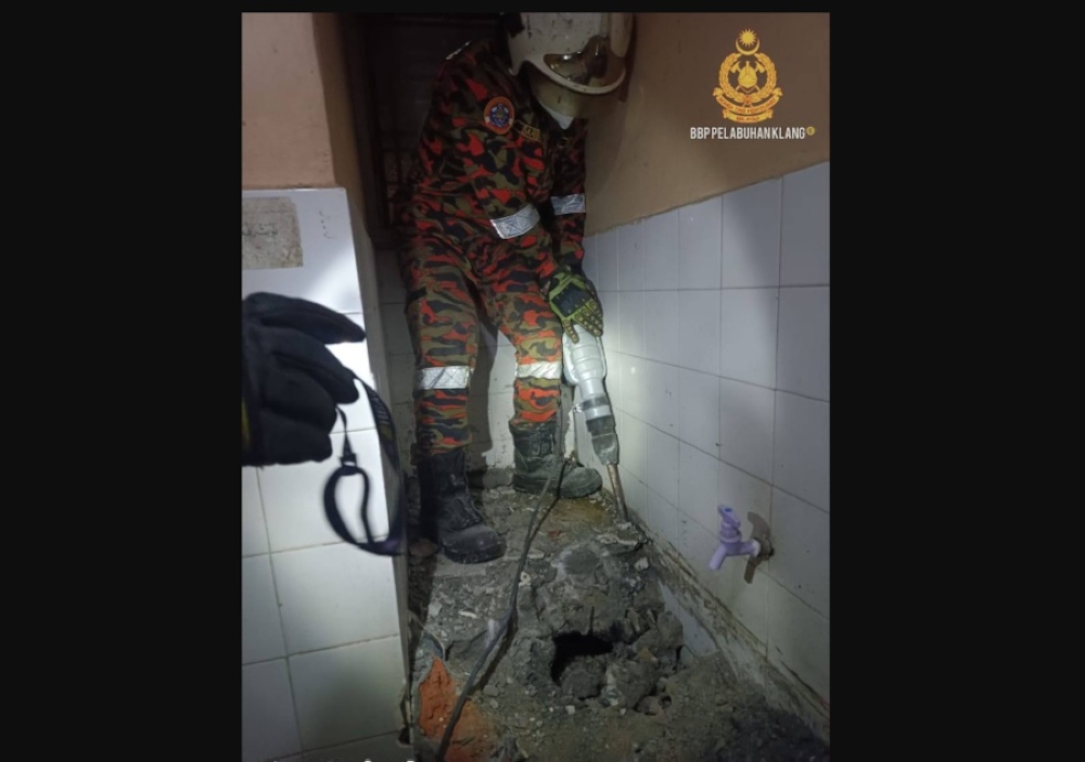 Fire and Rescue Department personnel extricating human remains from the cemented water tub. — Picture from X/BombaJBPM via Bernama TV