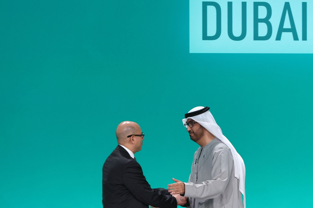 COP28 president Sultan Ahmed Al Jaber (right) and United Nations Framework Convention on Climate Change (UNFCCC) Executive Secretary Simon Stiell shake hands at a plenary session during the United Nations climate summit in Dubai on December 13, 2023. — AFP pic