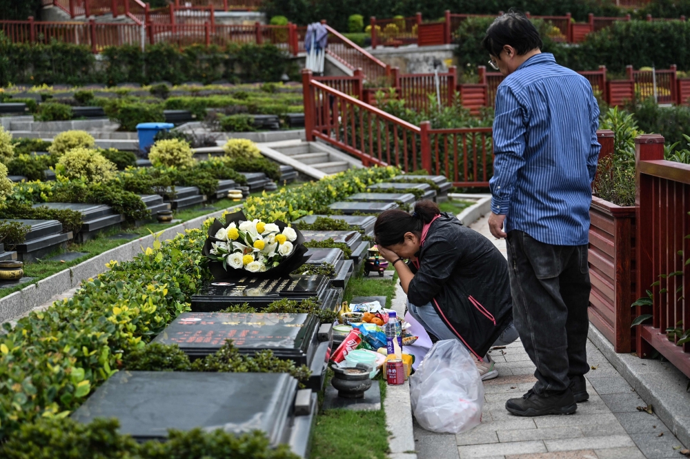 Seakoo Wu and his wife visiting the grave of their son Wu Xuanmo, who died last year. — AFP pic 