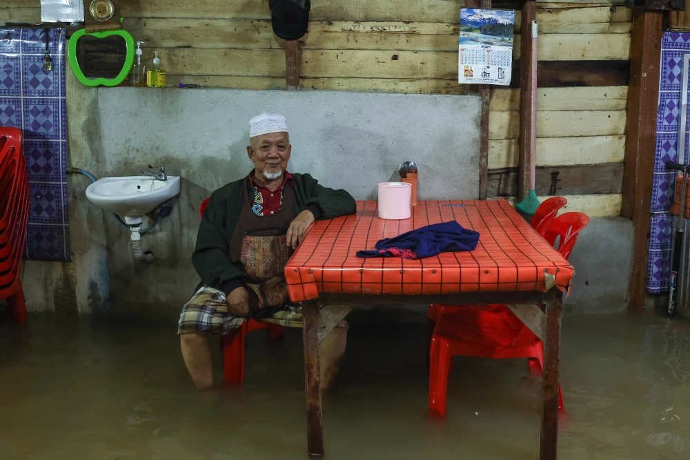 A man sits next to a table in a his flood-hit home, in Pasir Mas December 16, 2023. — Bernama pic