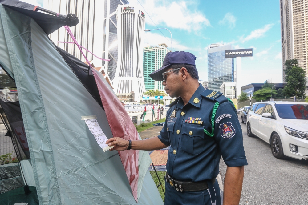 A DBKL officer checks a compound notice at a tent during the Kepung Demi Palestin picket at Jalan Tun Razak in Kuala Lumpur December 27, 2023. — Picture by Yusof Mat Isa