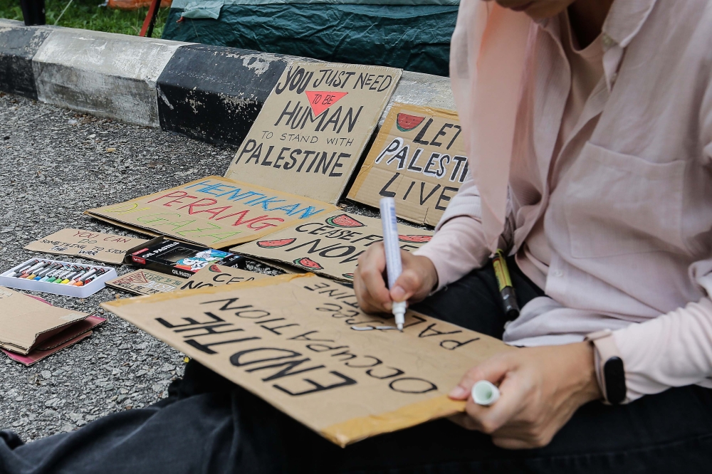 A picketer writes ‘End the occupation, free Palestine’ on a placard near the United States Embassy, Jalan Tun Razak, December 27, 2023. — Picture by Sayuti Zainudin