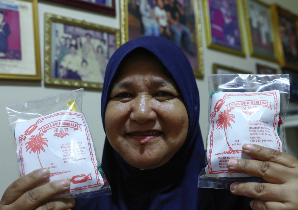 Confectionery entrepreneur Roziah Hussein poses with packets of ‘Coklat Nise Man’ at Taman Desa Kemumin, Padang Tembak, Pengkalan Chepa January 14, 2024. — Bernama pic