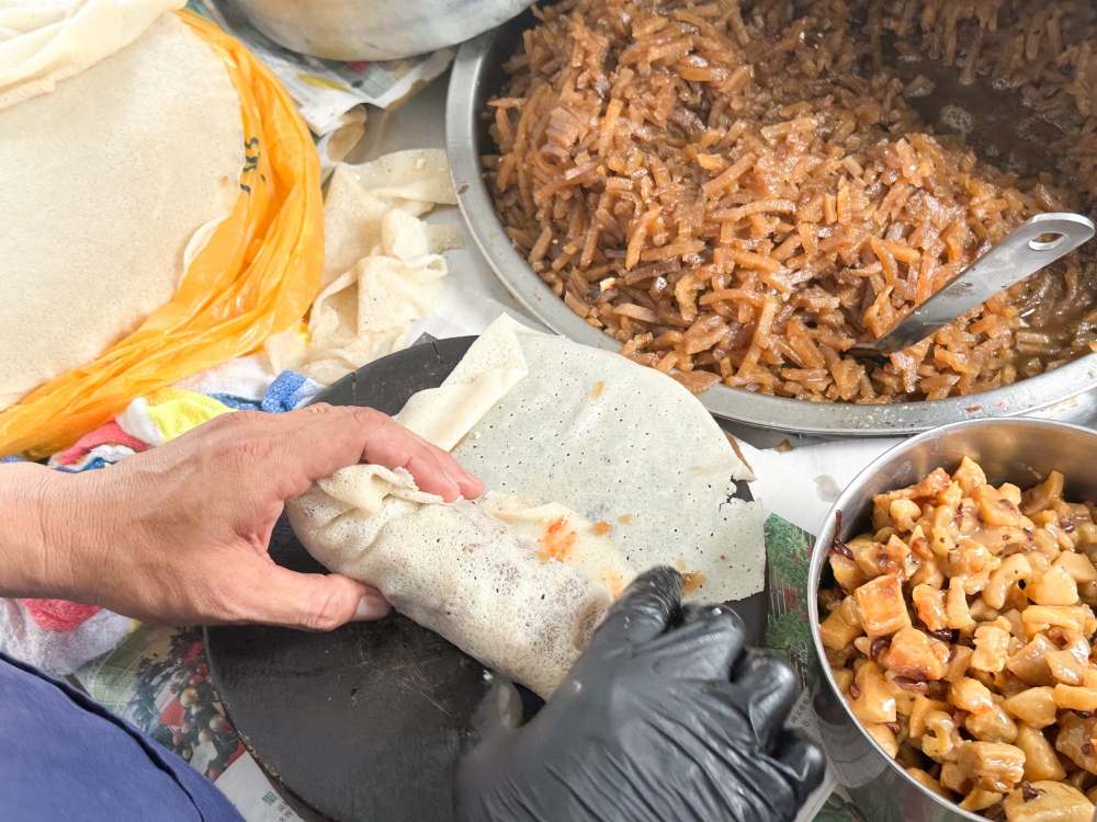 The 'popiah' skin is folded to cover the filling and the sides are tucked in, then it is rolled tightly to become a handheld roll,
