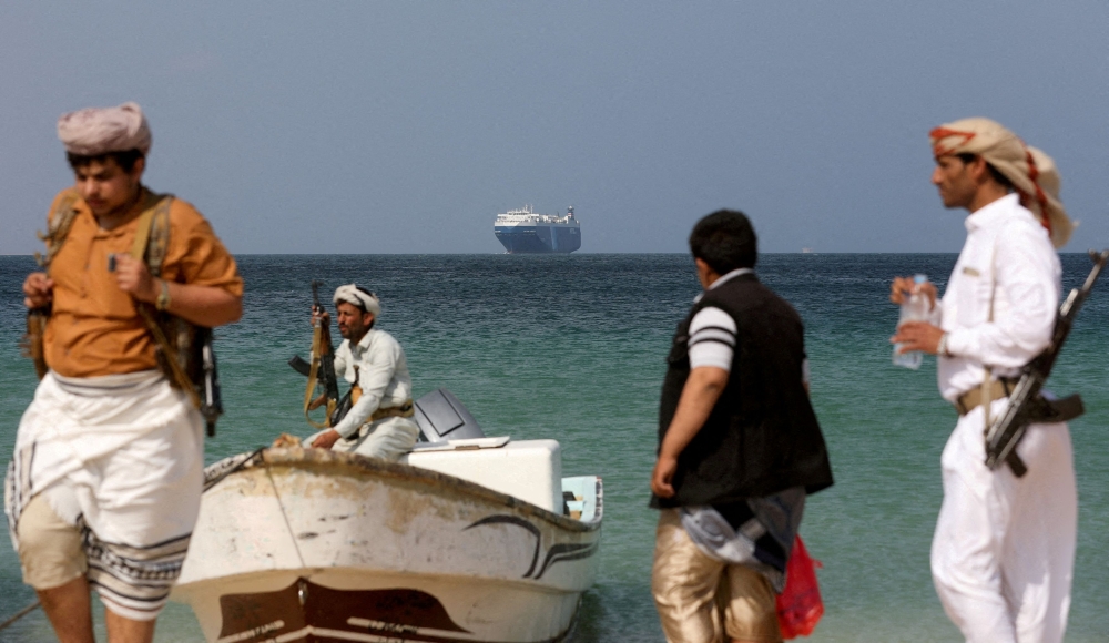 Armed men stand on the beach as the Galaxy Leader commercial ship, seized by Yemen's Houthis last month, is anchored off the coast of al-Salif, Yemen, December 5, 2023. ― Reuters pic