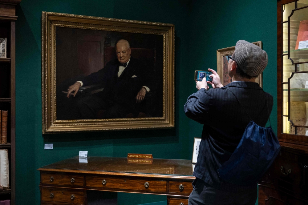 A man takes a picture of Winston Churchill’s personal desk and a portrait of the late British leader by Arthur Pan, part of the Winston S. Churchill Collection of Steve Forbes, at the Winter Show in New York City on January 18, 2024. ― AFP pic