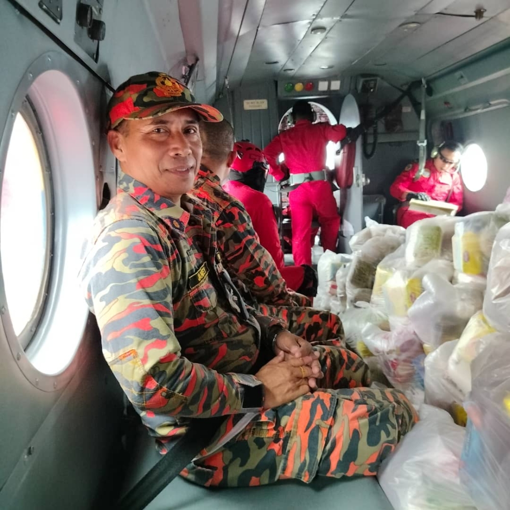 Fire and Rescue personnel in the helicopter during the delivery of food to Rh Dilang. — Picture courtesy of Fire and Rescue Department via Borneo Post Online