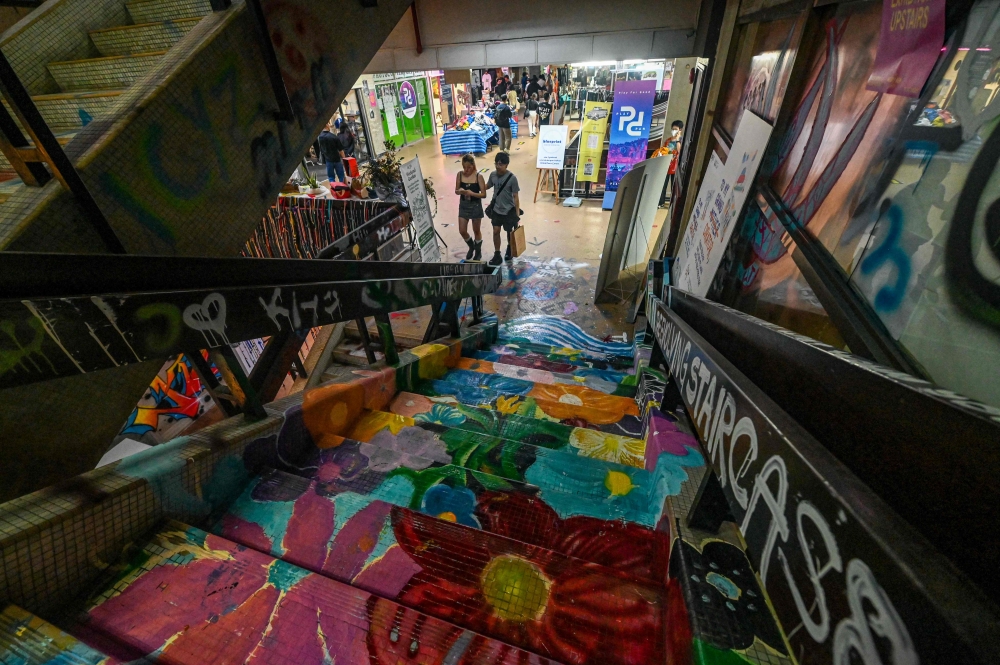 In this photograph taken on January 19, 2024, people walk past drawings and grafitti at the Peace Centre, an abandoned mall turned into an unexpected art enclave, in Singapore. — AFP pic