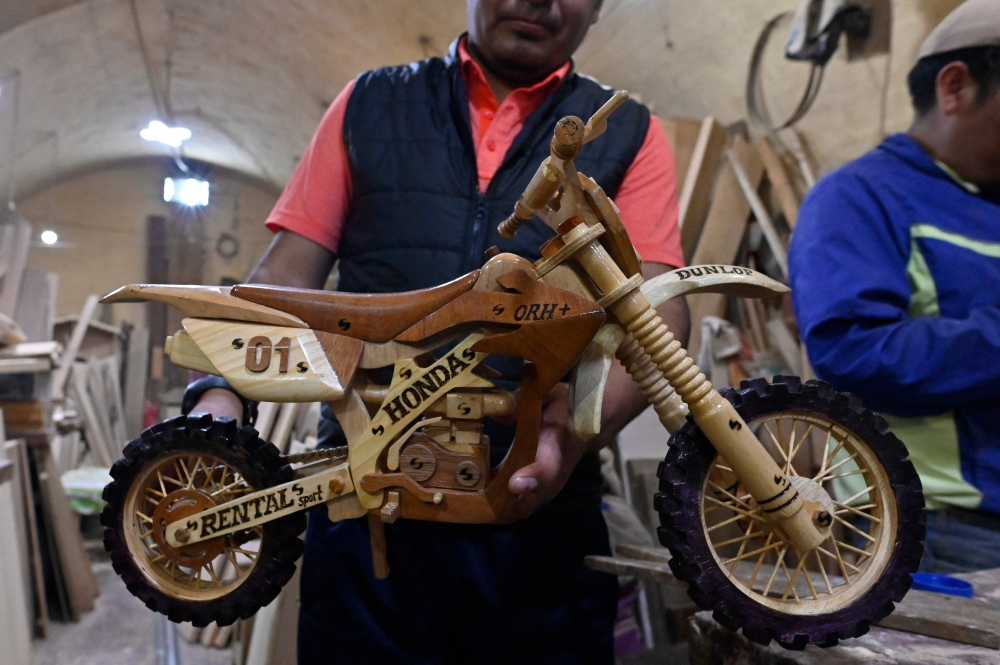 An inmate of the San Pedro prison shows a motorcycle made with wood that he made for its sale at the Alasita fair in La Paz, on January 18, 2024. — AFP pic