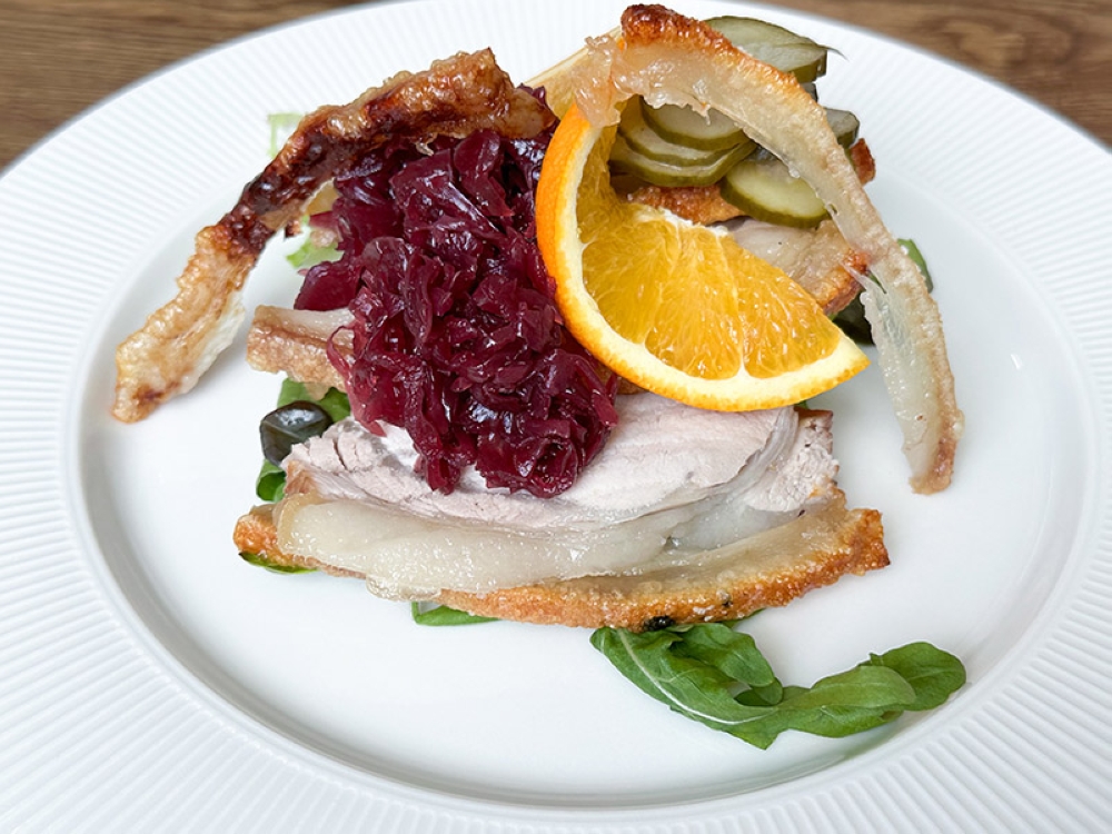 Roast Pork Loin with Crackling smørrebrød is topped with marinated red cabbage and a slice of orange