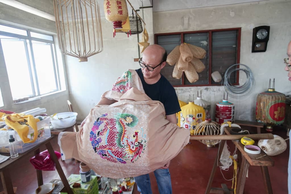 Chuen Mun Wai wraps the cloth onto the shaped bamboo before applying starch onto it. — Picture by Farhan Najib