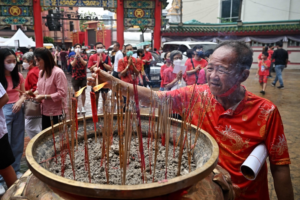 A man lights incense at Kuan Yim shrine in Chinatown in Bangkok. — AFP pic