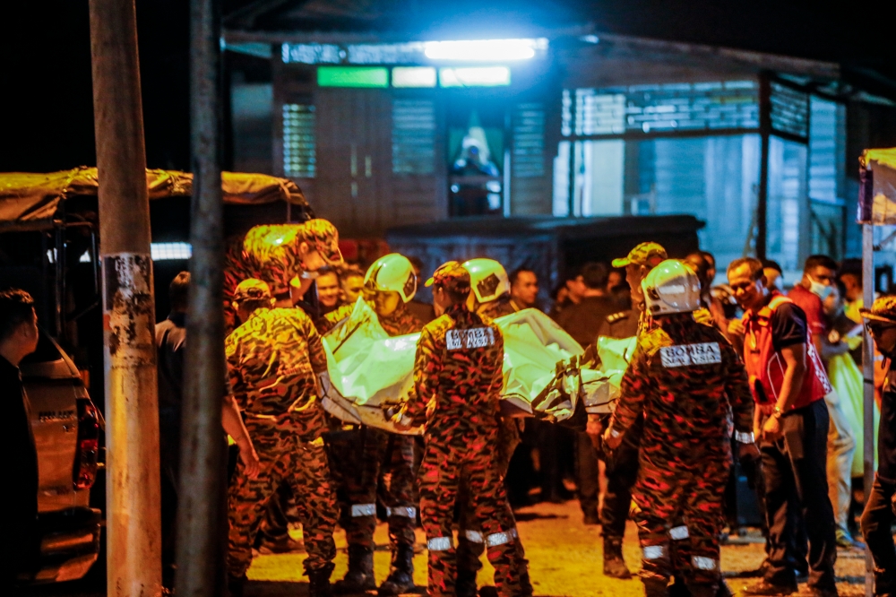 Fire and Rescue Department personnel carry the bodies of the two people, including one pilot, found on the scene in Kapar, Selangor February 13, 2024. — Picture by Hari Anggara