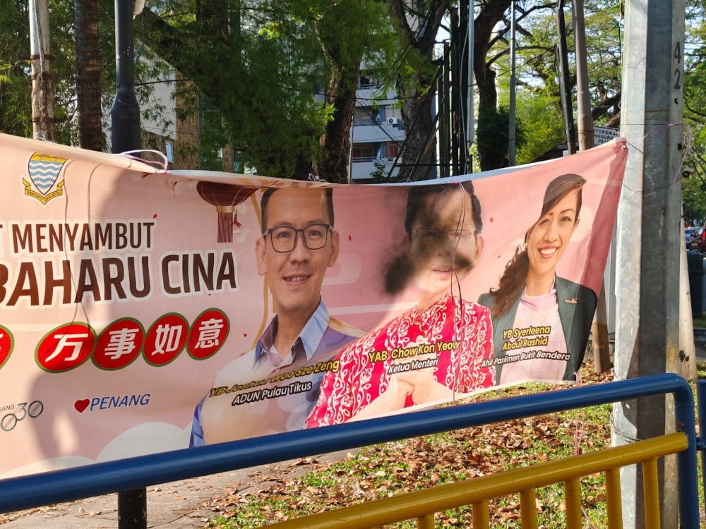 A banner vandalised with black spray paint marking X on Penang Chief Minister Chow Kon Yeow’s face. Some had the word ‘scam’ written on them. — Picture by Opalyn Mok 