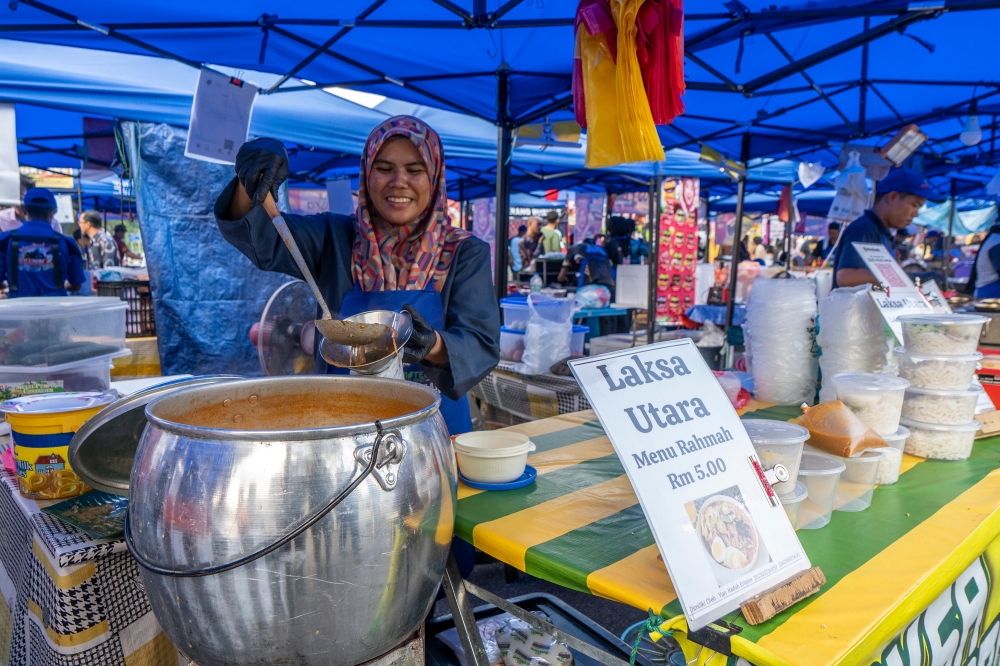 Nor Azian Aziz ladles out her laksa Utara at the Bazar Ramadan Rahmah at Bazar Ramadan Presint 14 in Putrajaya, March 14, 2024. — Picture by Shafwan Zaidon