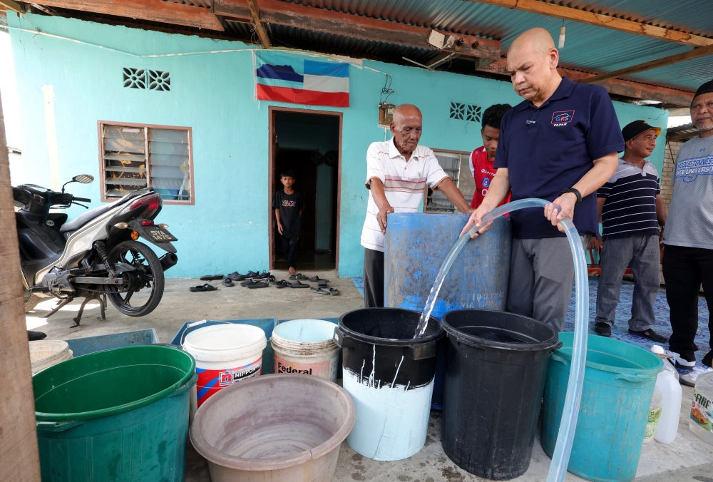 Minister of Domestic Trade and Cost of Living Datuk Armizan Mohd Ali fills clean water into containers provided by villagers when delivering clean water to the PPRT House in Kampung Kuala Dalam Papar March 17, 2024. — Bernama pic