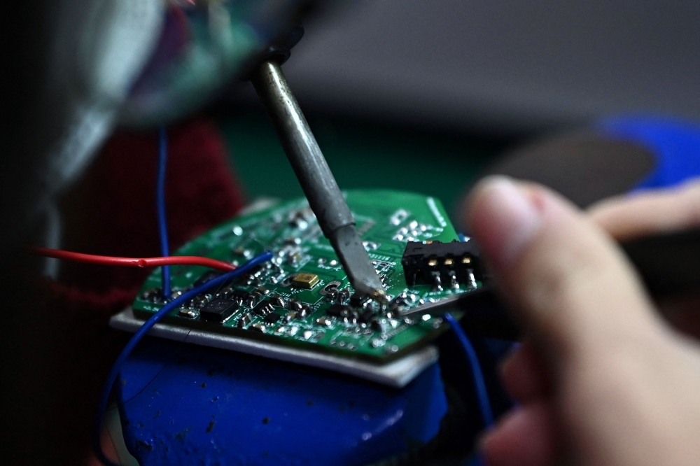 This photo taken on March 1, 2024 shows a student at Hanoi University of Science and Technology looking at a printed circuit board in the school's lab in Hanoi. — AFP pic