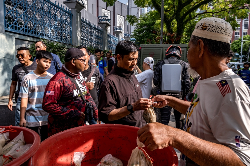People take Bubur Lambuk for breaking fast distributed by Masjid Jamek Kampung Baru during the Muslim holy fasting month of Ramadan in Kuala Lumpur March 20, 2024. — Picture by Firdaus Latif