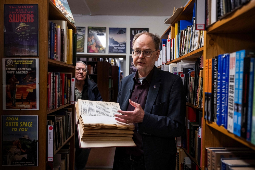 Archivists Clas Svahn (right) and Anders Liljegren stand between bookshelves at the Archives for the Unexplained (AFU) in Norrkoping, Sweden on March 12, 2024. — AFP pic