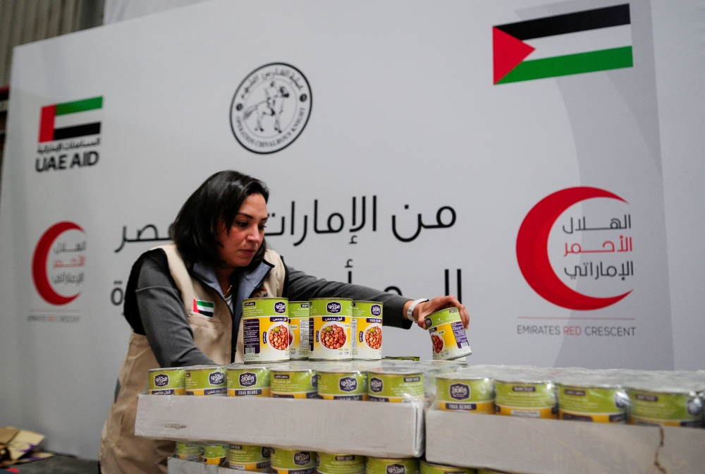 A volunteer from Emirates Red Crescent prepares parcels with humanitarian aid for Gaza to be transferred through the Rafah border crossing between Egypt and the Gaza Strip, in Cairo, Egypt, March 30, 2024. — Reuters pic 