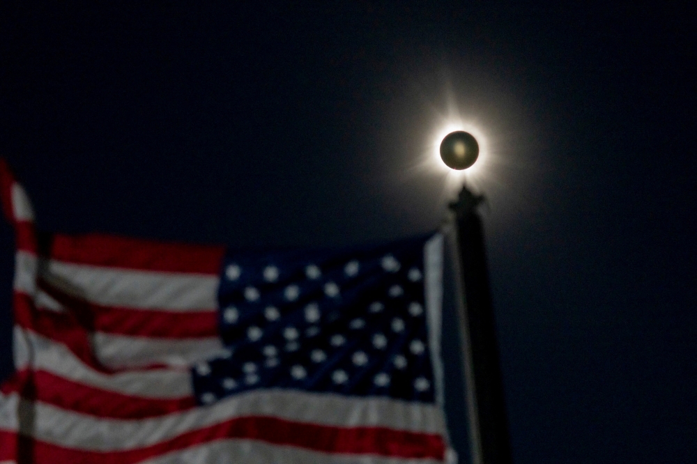 Eine totale Sonnenfinsternis ist neben einer wehenden amerikanischen Flagge in Houlton, Maine, am 8. April 2024 zu sehen. – Bild von Jasper Colt/USA Today Network über Reuters