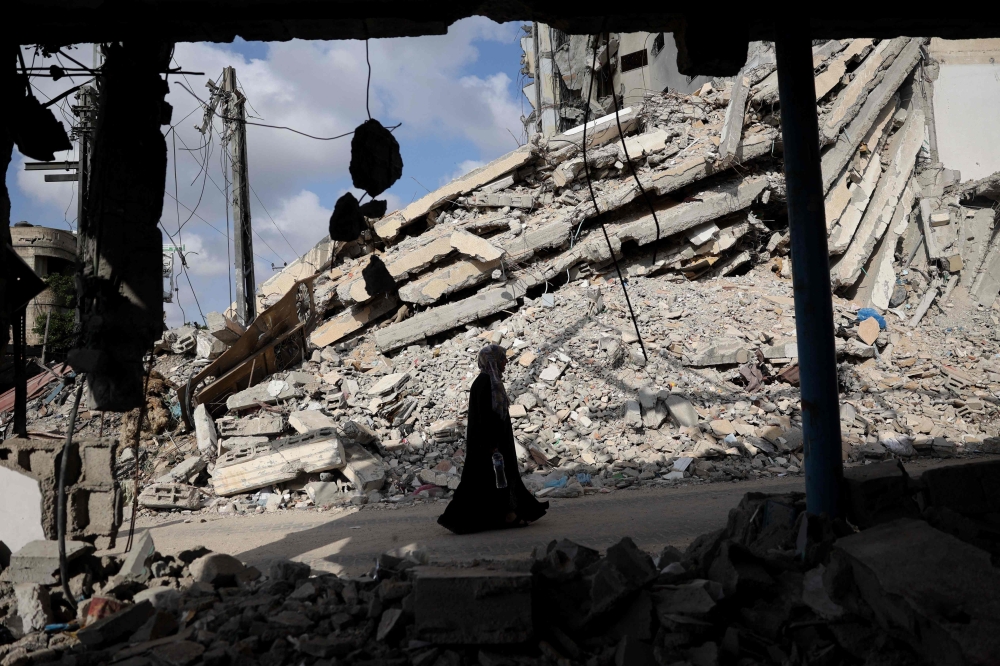 A Palestinian woman walks past the rubble of buildings destroyed in previous Israeli bombardments in Rafah. — AFP pic